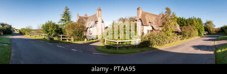 Dorchester, England, UK - September 19, 2012: Traditional thatched cottages stand beside a country lane in Frome St Quintin in the Dorset Downs. Stock Photo