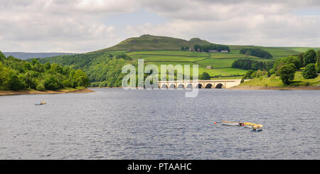 Row boats are moored in Ladybower Reservoir, in front of the A57 Snake Road bridge and Crook Hill in England's Peak District. Stock Photo