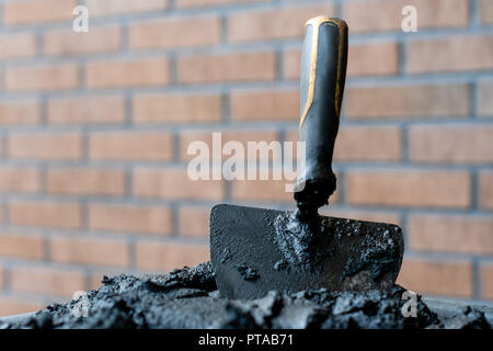 Bricklayers trowel in fresh mortar with bricks wall n the background. Stock Photo