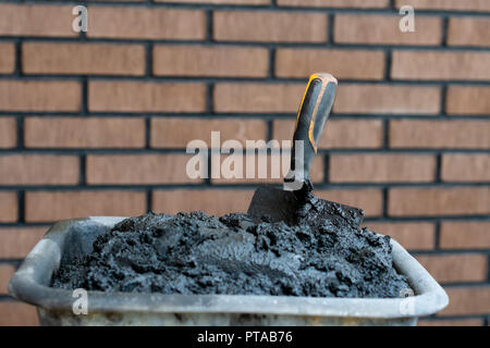 Bricklayers trowel in fresh mortar with bricks wall n the background. Stock Photo