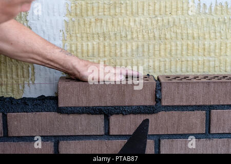 Bricklayer worker installing bricks on construction site. Stock Photo