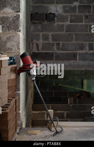 Electric drill with a mixer in a newly constructed building. Stock Photo