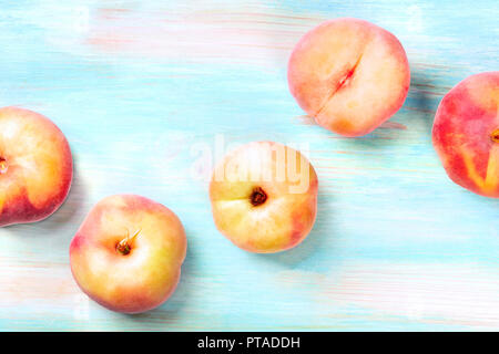 An overhead photo of vibrant organic flat saturn peaches, shot from above on a teal background with copy space Stock Photo