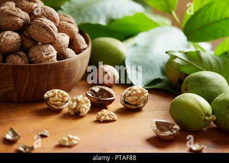 Fresh walnuts with and without shells on a wooden surface. Walnuts, shelled and unshelled. Stock Photo