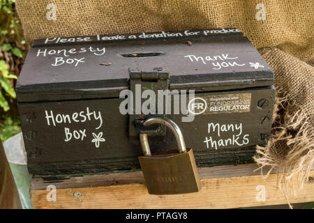 Old black wooden padlocked honesty cash box Stock Photo