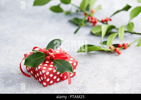 Christmas present wrapped with polka dot paper, and decorated with holly berries. Gift wrapped in polka dot paper with decorative red ribbon. Stock Photo