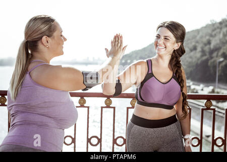 Delighted nice women giving high five to each other Stock Photo