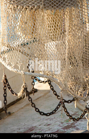 Fishing trawl net hanging on a trawler boat deck Stock Photo