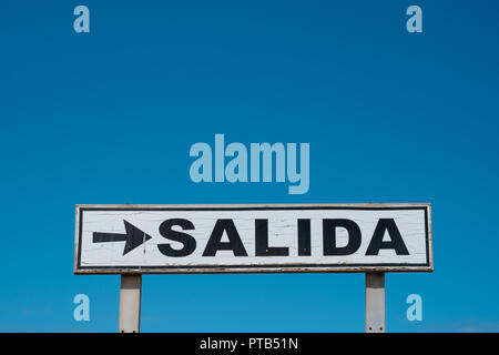 Exit sign (spanish: SALIDA) isolated on blue sky Stock Photo
