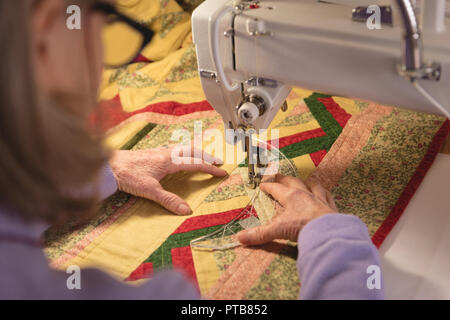 Woman sews clothes on sewing machine Stock Photo