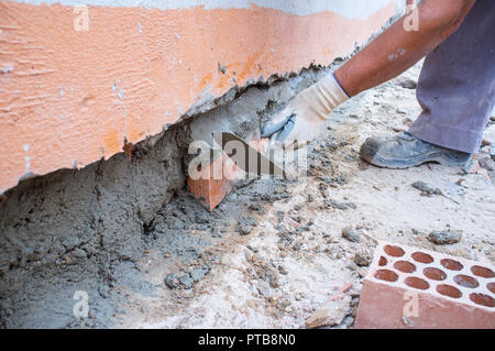 Bricklayer laying brick to cover a hole on wall. Closeup Stock Photo