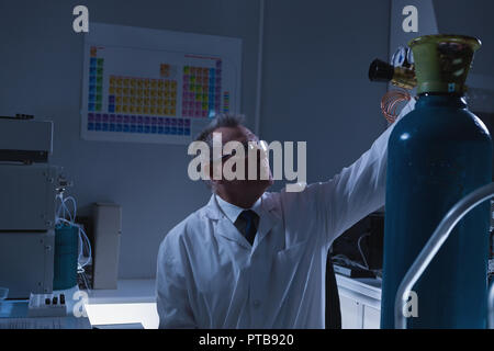 Male scientist adjusting pressure gauge of cylinder Stock Photo