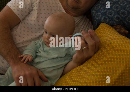 Father and baby boy relaxing on a sofa Stock Photo