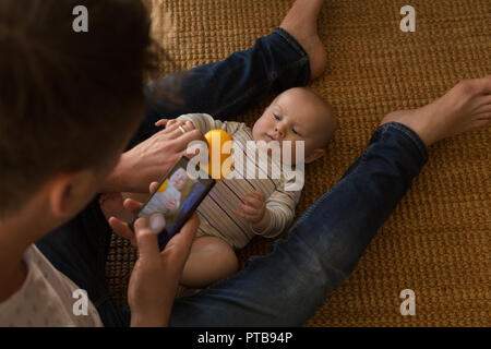Father clicking photo of his baby boy with mobile phone Stock Photo