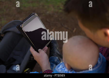 Father and baby boy using digital tablet in the park Stock Photo