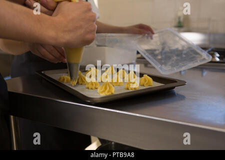 Chef using pastry bag in kitchen at restaurant Stock Photo