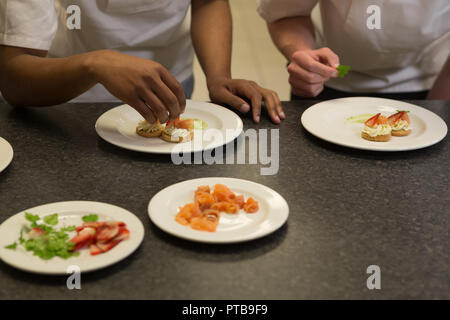 Chefs garnishing food on a plate Stock Photo