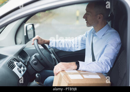 Delivery man with package driving a delivery van Stock Photo