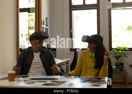 Business colleagues using virtual reality headset on desk Stock Photo