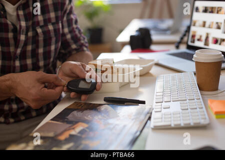 Businessman checking blood sugar with glucometer in office Stock Photo