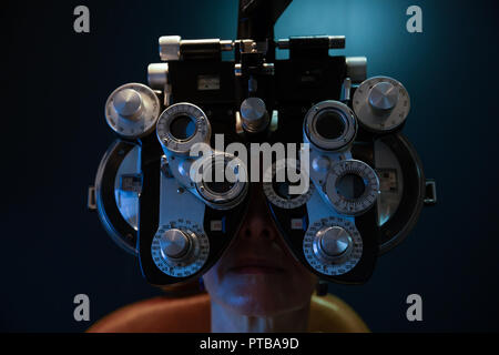 Optometrist examining patient eyes with phoropter in clinic Stock Photo