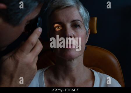 Optometrist examining patient eyes with ophthalmoscope Stock Photo