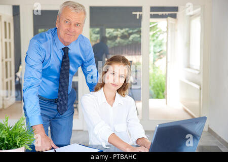 Shot of young and senior business people working together in the office. Young sales woman using notebook while senior businessman giving her some adv Stock Photo
