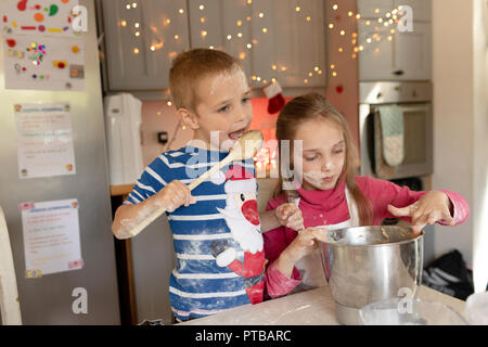 Siblings preparing and tasting the batter for Christmas cookies Stock Photo