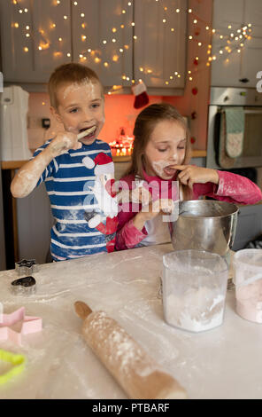 Siblings tasting the batter for Christmas cookies Stock Photo