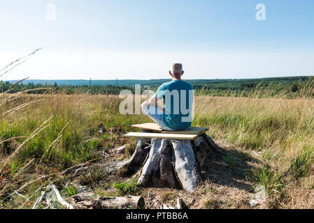 man sitting relax on a tree and yoga in the forest of the belgium nature park of the ardennes Stock Photo
