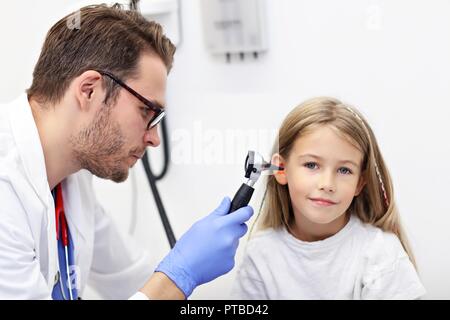 Male Doctor Examining Girl's Ear With An Otoscope Stock Photo