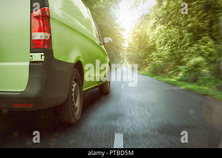 Green delivery van driving through the forest Stock Photo