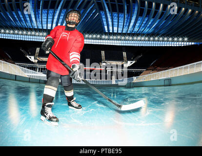 Portrait of teenage boy, hockey player, standing with stick on ice rink of stadium Stock Photo