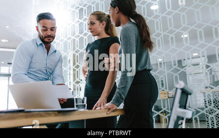Multi-ethnic business professionals discussing over a document boardroom. Business colleagues working on their new business plan together at office. Stock Photo