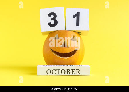 Pumpkin with halloween holiday calendar date against yellow background minimal creative concept. Stock Photo