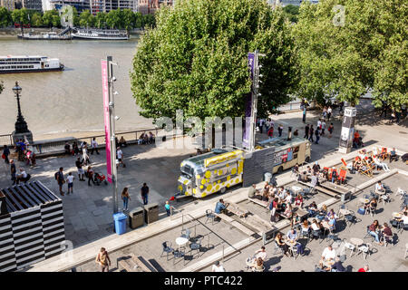 London England,UK,Lambeth South Bank,Thames River,riverside,Queen's Walk promenade,embankment,National Theatre theater plaza,food trailers,tables,crow Stock Photo