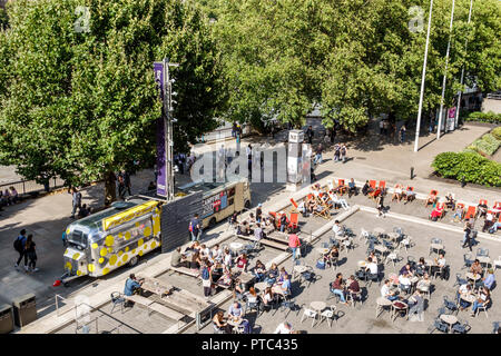 London England,UK,Lambeth South Bank,Thames River,riverside,Queen's Walk promenade,National Theatre theater plaza,food trailers,tables,crowd,deck chai Stock Photo