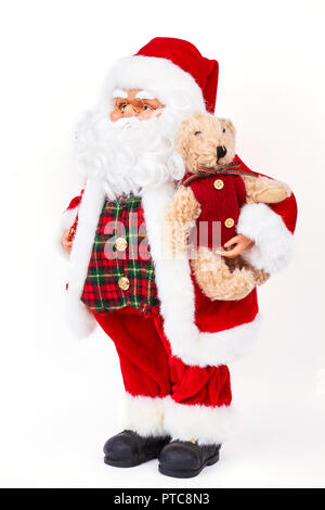 Santa Claus doll holding plush bear. Studio shot of plastic traditional greandfather frost holding cute brown teddy bear isolated on white background. Stock Photo