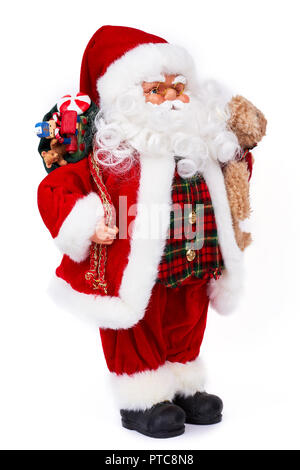 Cute old Santa Claus doll with gifts. Adorable grandfather frost toy holding Christmas presents and plush teddy bear standing isolated on white backgr Stock Photo