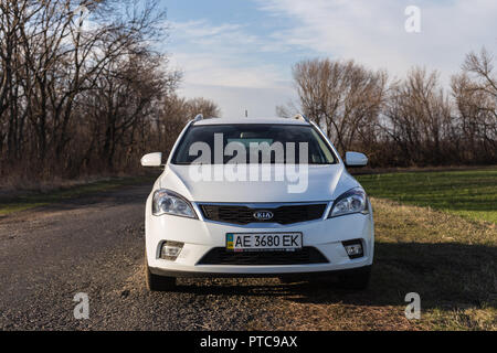 DNIPROPETROVSK REGION, UKRAINE - MARCH 25, 2015: KIA CEED WHITE COLOR ON THE ROAD THROUGH THE FIELDS Stock Photo