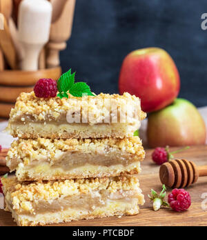 stack of square baked pieces of cake with apples on a wooden board, crumble cake Stock Photo