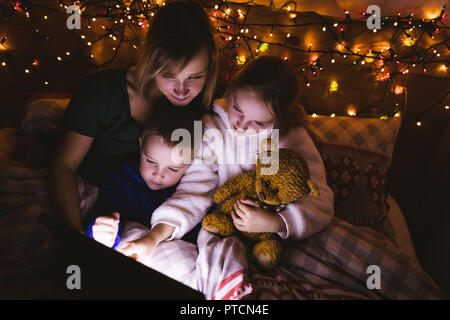 Mother and kids using digital tablet on bed Stock Photo