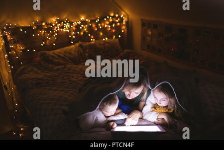 Mother and kids under the blanket using digital tablet Stock Photo