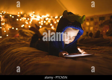 Boy in blue jacket using digital tablet against Christmas lights Stock Photo