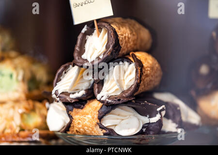 Closeup of chocolate cannoli stuffed with cream cheese whipped filling dessert on glass plate window display in gourmet bakery Italian cafe with golde Stock Photo