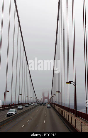 Driving across the Golden Gate Bridge on a very foggy day with the towers shrouded in fog, San Francisco, California, USA Stock Photo