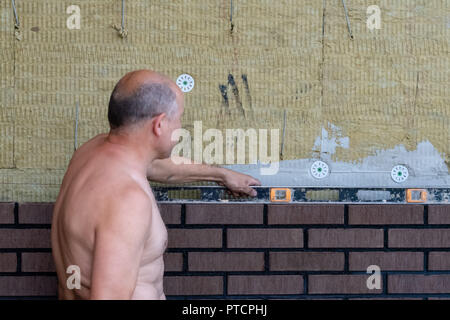 Bricklayer Using a Spirit Level to Check New Red Brick Wall Outdoor. Stock Photo