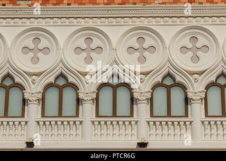 Abstract French balconies which decorated in circle shape above arch door on stucco wall background. Stock Photo