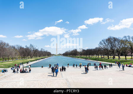Washington DC, USA - April 5, 2018: Washington Monument and people by Lincoln Memorial and reflecting pool on national mall during green spring sunny  Stock Photo