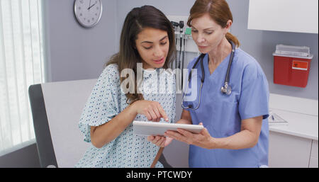Closeup of senior nurse using tablet computer to share test results with patient Stock Photo